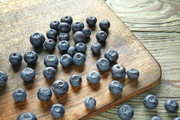 Wooden board with fresh blueberry on table