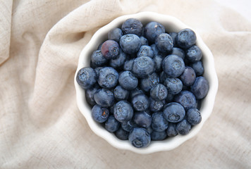 Bowl with fresh blueberry on table