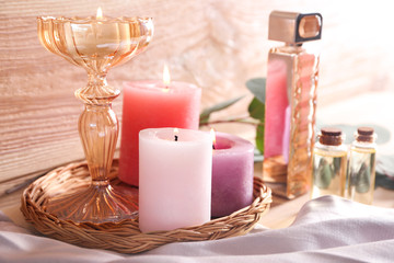 Beautiful burning candles with essential oil and bottle of perfume on table