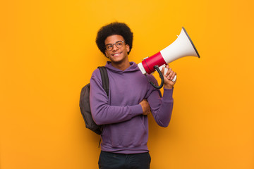 Young african american man holdinga a megaphone smiling confident and crossing arms, looking up