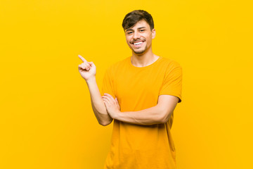 Young hispanic casual man smiling cheerfully pointing with forefinger away.