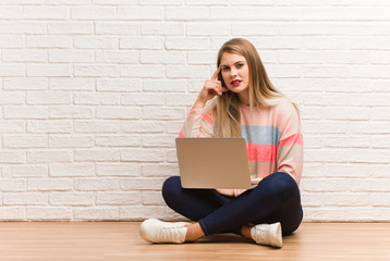 Young russian student woman sitting doing a disappointment gesture with finger