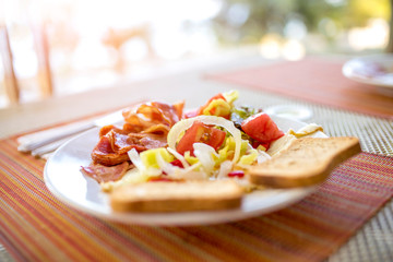 Plate with fried eggs, bacon, tomatoes, onions, paprika and toasted bread