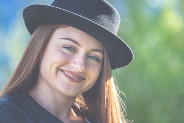 Junge Frau mit Lederjacke und Hut im Garten - Frühling und Sonnenschein im Grünen genießen.