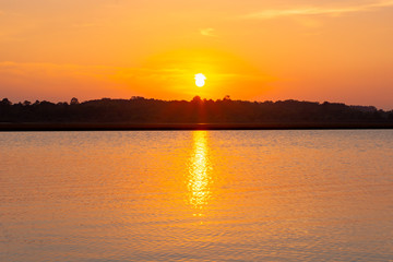 Sunset reflection lagoon. beautiful sunset behind the clouds and blue sky above the over lagoon landscape background. dramatic sky with cloud at sunset