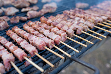 Closeup of meat skewers being grilled in a barbecue shrouded with smoke
