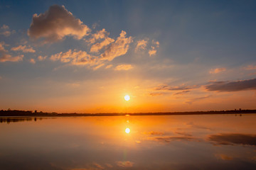 Naklejka premium Sunset reflection lagoon. beautiful sunset behind the clouds and blue sky above the over lagoon landscape background. dramatic sky with cloud at sunset