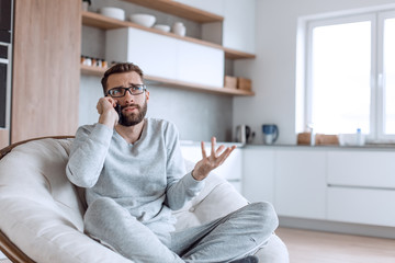 cheerful man talking on a mobile phone sitting in a comfortable chair