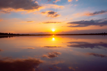 Obraz na płótnie Canvas Sunset reflection lagoon. beautiful sunset behind the clouds and blue sky above the over lagoon landscape background. dramatic sky with cloud at sunset