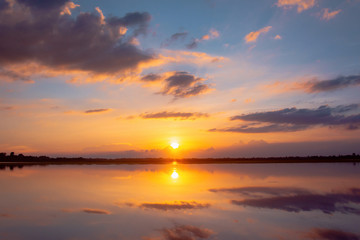 Obraz na płótnie Canvas Sunset reflection lagoon. beautiful sunset behind the clouds and blue sky above the over lagoon landscape background. dramatic sky with cloud at sunset