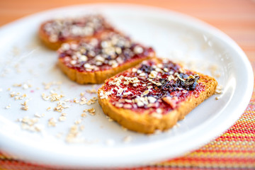 Plate with toasted bread with blueberry jam and oats flakes