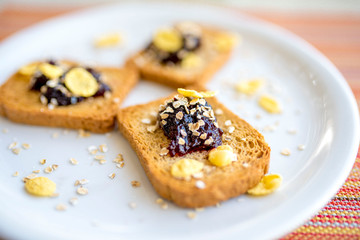 Plate with toasted bread with blueberry jam and oats and corn flakes