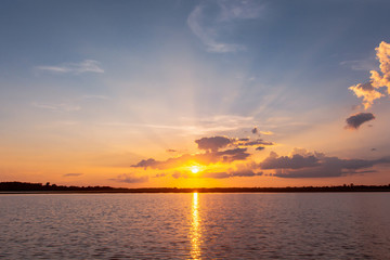 Obraz premium Sunset reflection lagoon. beautiful sunset behind the clouds and blue sky above the over lagoon landscape background. dramatic sky with cloud at sunset