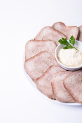 Beef boiled tongue with horseradish on a white plate. White background, isolated. Place for text. Close-up.