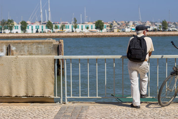 Old man with a bike looking at river in Portim&atilde;o Algarve Portugal