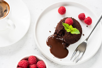 Chocolate lava cake or molten core cake with raspberries on white plate