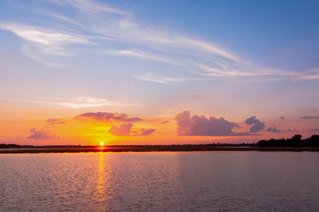 Sunset reflection lagoon. beautiful sunset behind the clouds and blue sky above the over lagoon landscape background. dramatic sky with cloud at sunset