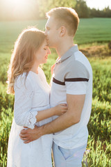 Obraz premium Young pretty couple in love standing in park. Handsome cheerful blonde girl in white dress hugging her boyfriend. Man and woman having fun outdoors