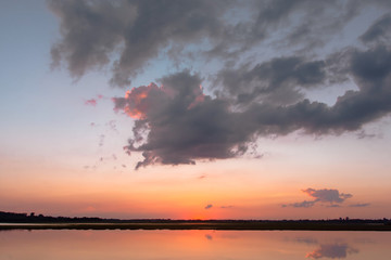 Sunset reflection lagoon. beautiful sunset behind the clouds and blue sky above the over lagoon landscape background. dramatic sky with cloud at sunset