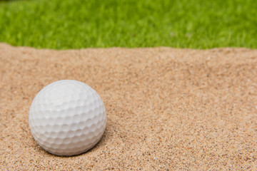 White golf ball in sand bunker on golf court.