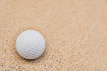 Selective focus of white golf ball on sand bunker