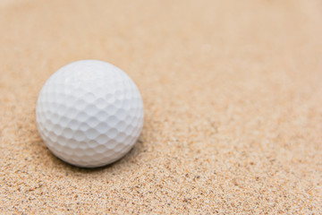 Selective focus of white golf ball on sand bunker