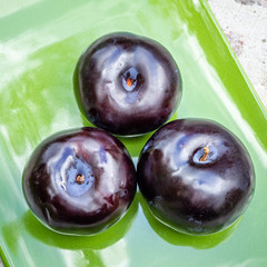 Three dark purple plum fruits close up
