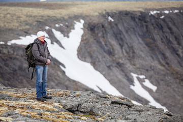 Obraz premium Mature Caucasian man mountain tourist standing on cliff and looking on stone valley, copy space
