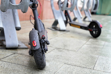 Electric scooters on a parking lot during a rain, water drops on a wheels. Rainy weather in a city, bike rental system