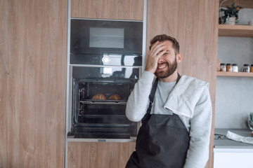 surprised man standing near the oven with burnt croissants.