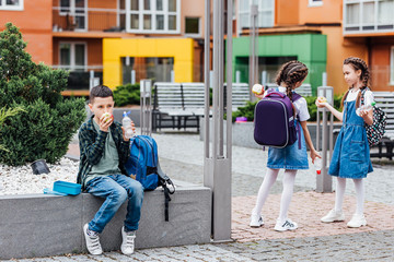 Multiethnic group of schoolkids eating lunch while have break time.