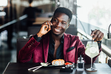 Attractive african boy have a sushi time in caffe shop or in restaurant terrace in summer time.