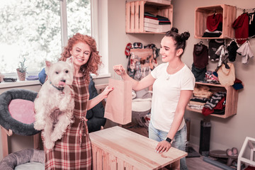 Curly red-haired woman feeling happy after shopping in pet shop