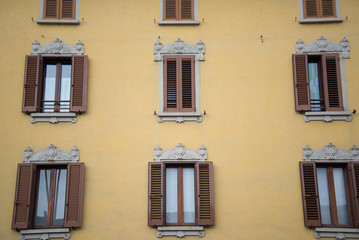 Fototapeta na wymiar Decorated windows of a historical building in Caravaggio, Italy