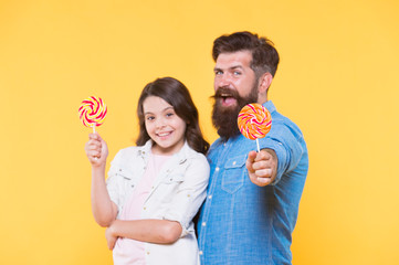 Sweet childhood. Girl child and dad hold colorful lollipops. Sweets and treats concept. Daughter and father eat sweet candies. Sweet dessert. Bearded hipster good daddy for adorable daughter