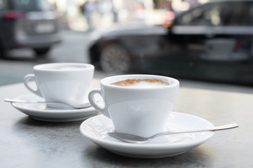 Two cups of cappuccino on a textured grey background. Street cafe. Close-up.
