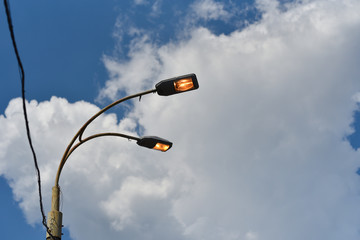 Concept of not energy saving. Power on of street lighting in day