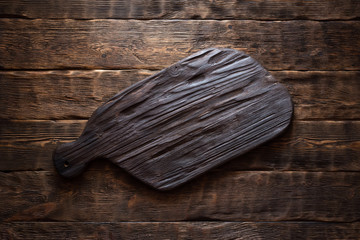 Old cutting board with a copy space for food on a aged wooden kicthen board background.