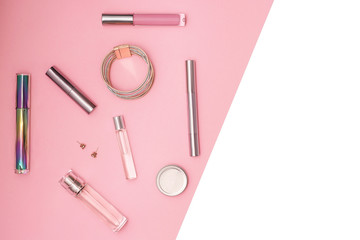 Flat lay composition with decorative makeup products and gold chain necklace on pastel pink background. Makeup and beaty concept. Copy space.