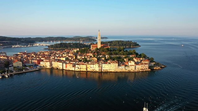 4K. Flight over beautiful Rovinj at sunrise. Morning aerial panoramic view of the old town of Rovinj, church of St. Euphemia and islands, Istria, Croatia.