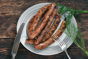 A grilled sausages on a plate on a kitchen table background.