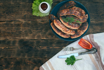 A grilled sausages on a plate on a kitchen table background.
