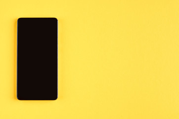 Black cellphone on yellow background composition, mobile phone.