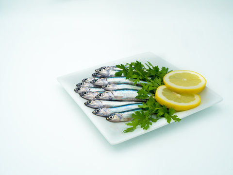 Fresh anchovies in a plate accompanied by lemon and parsley