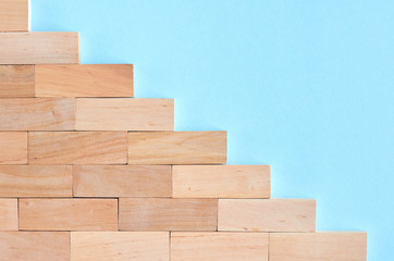 Brown wooden blocks stairs shape idea on blue background composition.