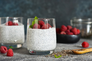 Chia pudding with yogurt and raspberries in a glass on concrete background