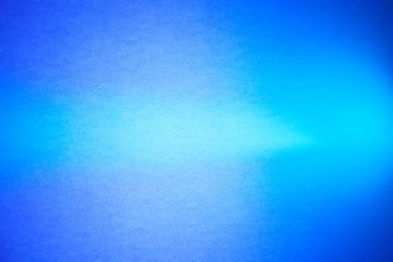 Light turquoise ray of light in the middle of the blue and purple textural semi-blurred background