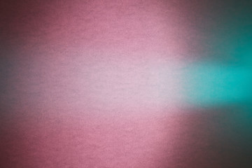 On a dark pink textural and blurred dark turquoise background turquoise ray of light