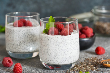 Chia pudding with yogurt and raspberries in a glass on concrete background