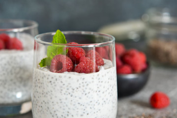 Chia pudding with yogurt and raspberries in a glass on concrete background